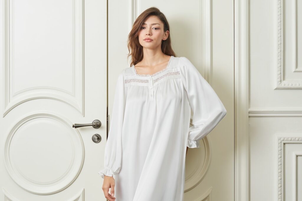 A woman in a MANITO white silk nightdress expressing airy spring and summer elegance at home.